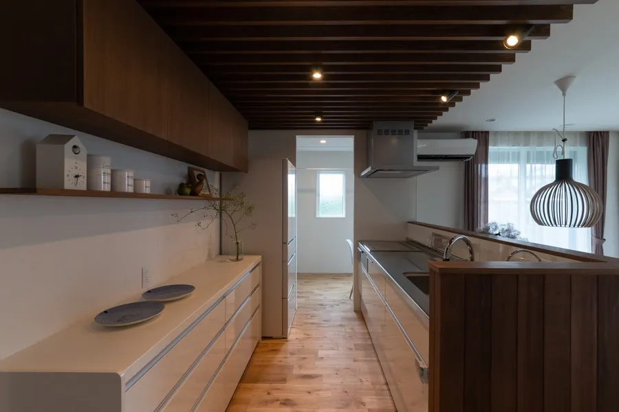 キッチンの天井にはルーバーをアクセントに。わざと天井を低く見せることでリビングへの開放感をより感じることができる
