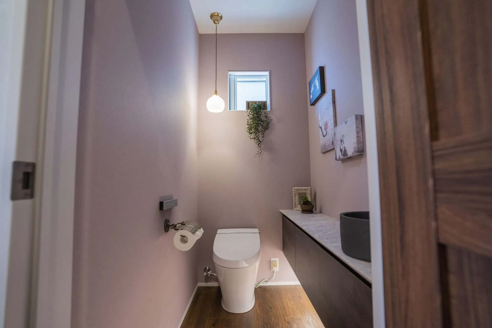 くすみピンクのクロスが海外っぽくて可愛いトイレは少し広めにプラン。造作収納カウンターには間接照明を細工しモダンさをプラス